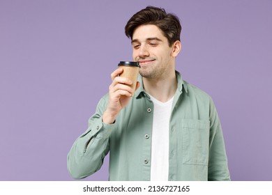 Young Excited Satisfied Fun Man 20s In Casual Green Mint Shirt White T-shirt Holding Paper Cup Of Coffee Drink Hot Tea In Morning Sniff With Closed Eyes Isolated On Purple Background Studio Portrait