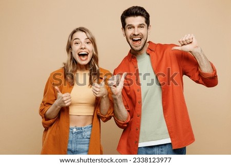 Young excited surprised shocked couple two friends family man woman wear casual clothes point finger on himself show thumb up together isolated on pastel plain beige color background studio portrait