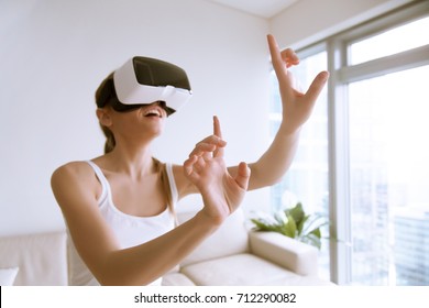 Young excited woman wearing VR headset touching objects in virtual world, using goggles mobile application for innovative education, shopping in 3d store, interacting with digital headset interface