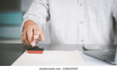 A Young Executive Is Stamping On Documents For A Business Contract. Transaction And Document Management Concepts Include Negotiating Corporate Entities And Filling Out Legal Forms Or Agreements.