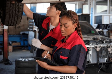 Young expertBlack female inspects repair checklist with automotive mechanic worker partner, quality suspension technician team at fix garage. Vehicle maintenance service works industry occupation job. - Powered by Shutterstock