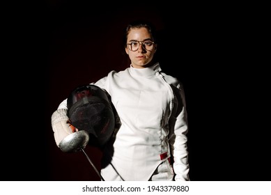 Young and expressive girl wearing fencing suit looking at camera against black background. - Powered by Shutterstock