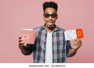 Young Exultant Jubilant Cheerful Excited Man Of African American Ethnicity In 3d Glasses Watch Movie Film Hold Bucket Of Popcorn In Cinema Ticket Isolated On Plain Pastel Light Pink Background Studio