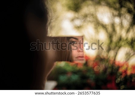Young Woman’s Face Reflected in a Small Mirror Outdoors