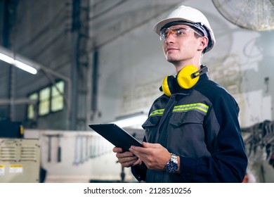 Young factory worker using adept tablet computer in a workshop building . Industrial technology and manufacturing software configuration .