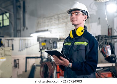 Young factory worker using adept tablet computer in a workshop building . Industrial technology and manufacturing software configuration . - Powered by Shutterstock