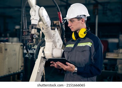 Young factory worker working with adept robotic arm in a workshop . Industry robot programming software for automated manufacturing technology . - Shutterstock ID 2151666065