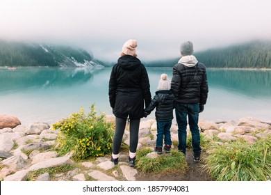 Young Family Admiring The View At Lake Louise On A Foggy Day