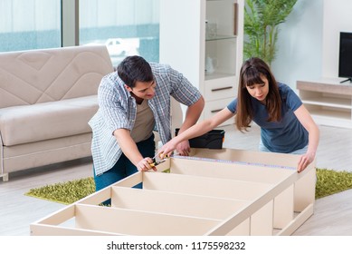 Young Family Assembling Furniture At New House