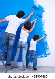 Young Family Brushing The Wall Together Into The Blue Color