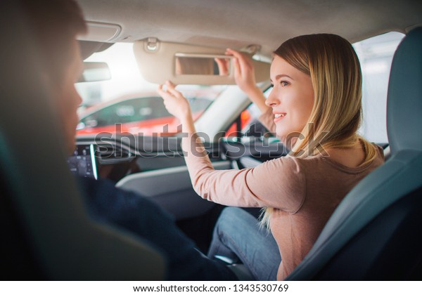 Young family buying first electric car in the
showroom. Attractive smiling couple talking in the cabin of modern
electric hybrid vehicle before test driving. Electric car sale
concept
