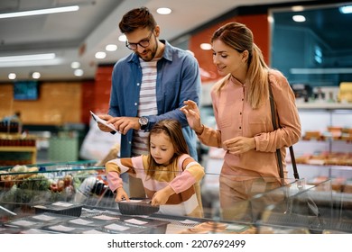 Young Family Buying Food At Refrigerated Section In Supermarket.