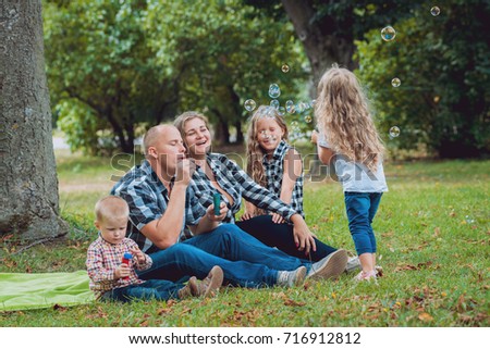 Young family with cheerful children in the park. Bubble blower