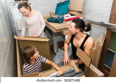 Young Family With A Child In A New Apartment With Boxes And Packages