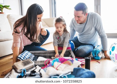 Young Family With A Child Packing For Holiday.