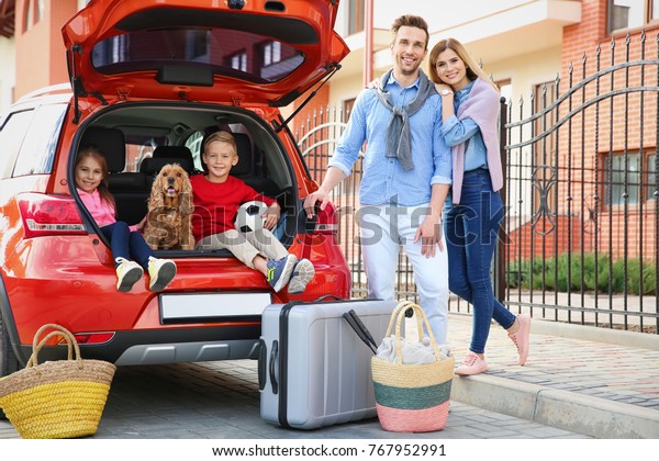 Young family with\
children and dog near car