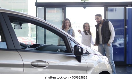 Young Family Comes Into Car Dealership To Choose The Car To Buy It.