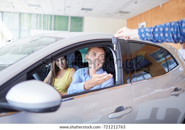 Young family comes into Car dealership to choose the\
car to buy it.