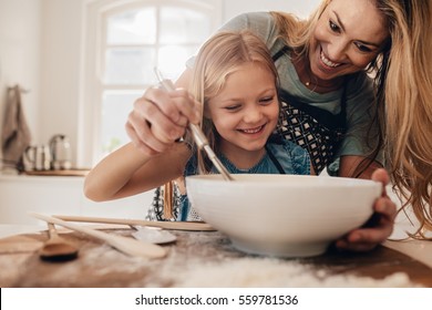 Молодая семья готовит еду на кухне. Счастливая молодая девушка с матерью смешивания тесто в миске.