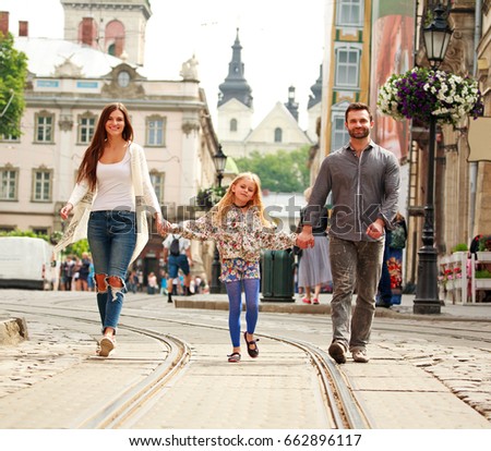 Young family couple with daughter walking the street of the old tourist city