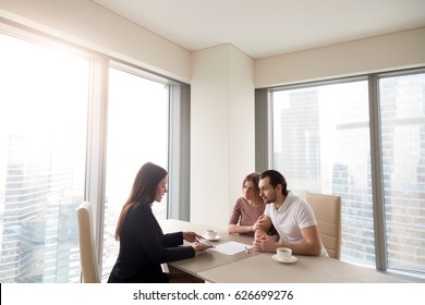 Young Family Couple Meeting With Bank Worker To Sign Loan Contract, Discussing Banking Credit, Personal Insurance Or Mortgage Investment, Manager Showing Clients Build Project On Tablet 