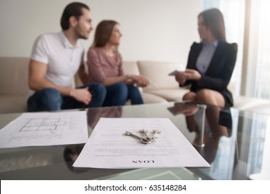 Young Family Couple Sitting On Sofa Discussing First Mortgage With Agent, Focus On Loan Agreement And Keys, Taking Bank Credit With Easy Terms Of Payment And Low Interest Rate For Purchasing Property