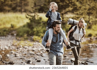 Young family crossing a creek while hiking in the forest and mountains - Powered by Shutterstock