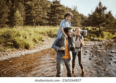 Young family crossing a creek while hiking in the forest and mountains - Powered by Shutterstock
