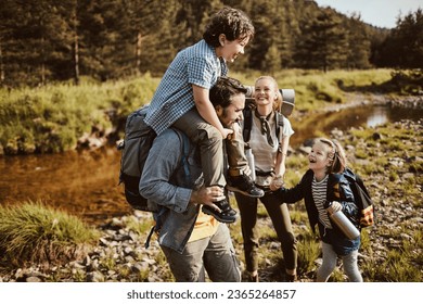 Young family crossing a creek while hiking in the forest and mountains - Powered by Shutterstock