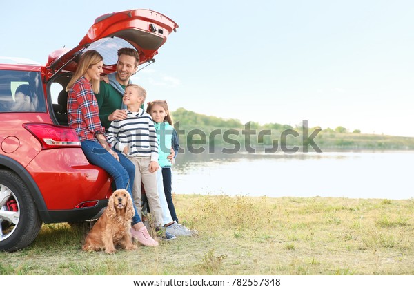 Young family\
with cute children and dog near\
car