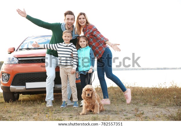 Young family\
with cute children and dog near\
car