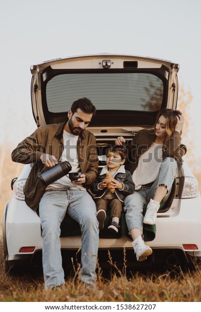 Young family with cute little son having picnic in\
car trunk.