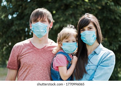 Young Family With Daughter Wearing Protective Surgical Face Masks During The Covid-19 Or Coronavirus Pandemic