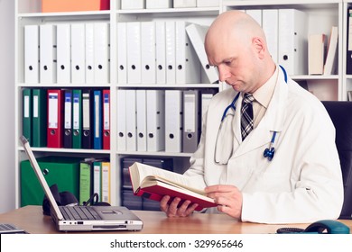 Young Family Doctor In His Office  Reading A Book