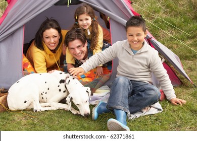 Young Family With Dog Relaxing Inside Tent On Camping Holiday