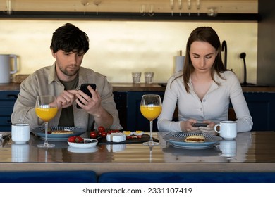 Young family drinks coffee and looks at smartphones. A young couple using smartphones ignore each other. use mobile apps or check social networks online. steam and technological concept - Shutterstock ID 2331107419