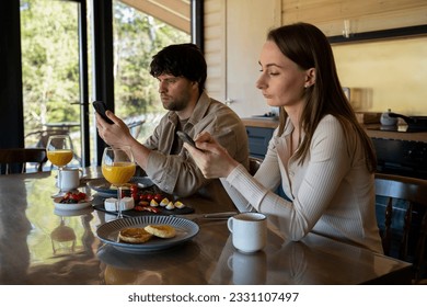 Young family drinks coffee and looks at smartphones. A young couple using smartphones ignore each other. use mobile apps or check social networks online. steam and technological concept - Shutterstock ID 2331107497
