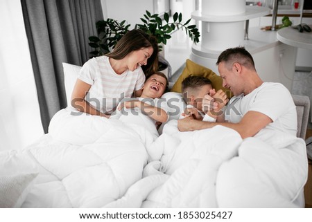 Similar – Mother reading book to her sons in the bed