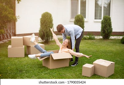 Young Family Enjoying Moving Day, Being Silly Together In Front Yard Of Their New House. Panorama