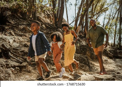 Young family enjoying their holidays in a national park. African family walking down a mountain trail and having fun.