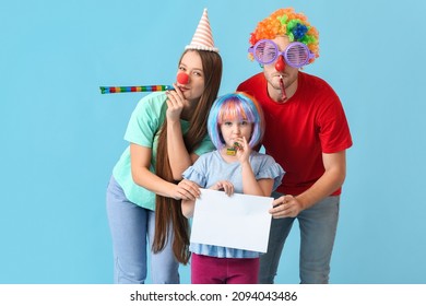 Young family in funny disguise and with empty paper sheet on color background. April Fools Day celebration