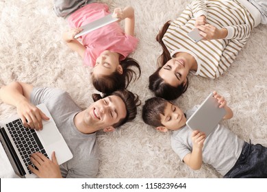 Young family with gadgets at home, top view