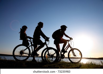 Young family go for a cycle ride on the beach at background sunset - Powered by Shutterstock