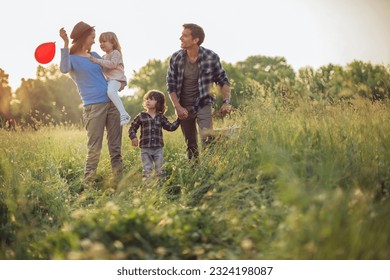 Young family going on the picnic in a field next to a forest