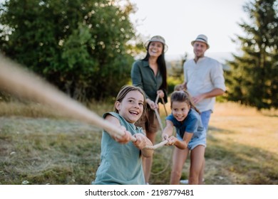 Young family with happy kids having fun together outdoors pulling rope in summer nature. - Powered by Shutterstock