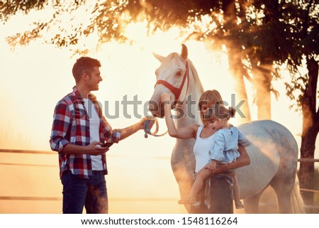 Young family have a fun with a beautiful horse on the countryside.