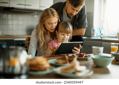 Young family having breakfast at home while using a digital tablet - Powered by Shutterstock