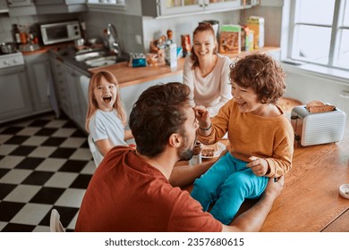 Joven familia desayunando juntos y siendo desordenada en la cocina