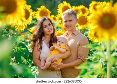 Young Family Having Fun In The Field Of Sunflowers In Summer. Father And Mother Holding Little Baby Daughter. Summer Season, Freedom, Family Value Concept.