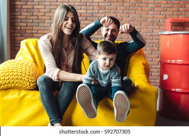 Young Family Having Fun On The Big Yellow Couch